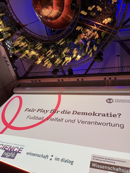 Eine Präsentation auf einer großen Leinwand. Auf der Präsentation steht: 