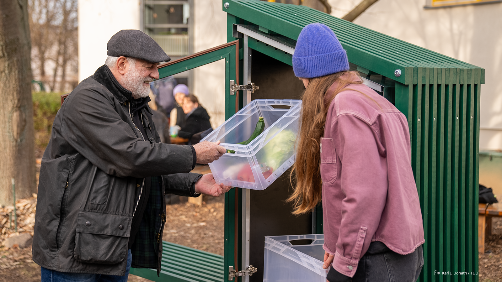 Foto von Prof. Michael Vaerst und Johanna Edelmann am "Fairteiler", die daraus eine Kiste mit Lebensmitteln entnehmen. Foto von Prof. Michael Vaerst und Johanna Edelmann am "Fairteiler", die daraus eine Kiste mit Lebensmitteln entnehmen.