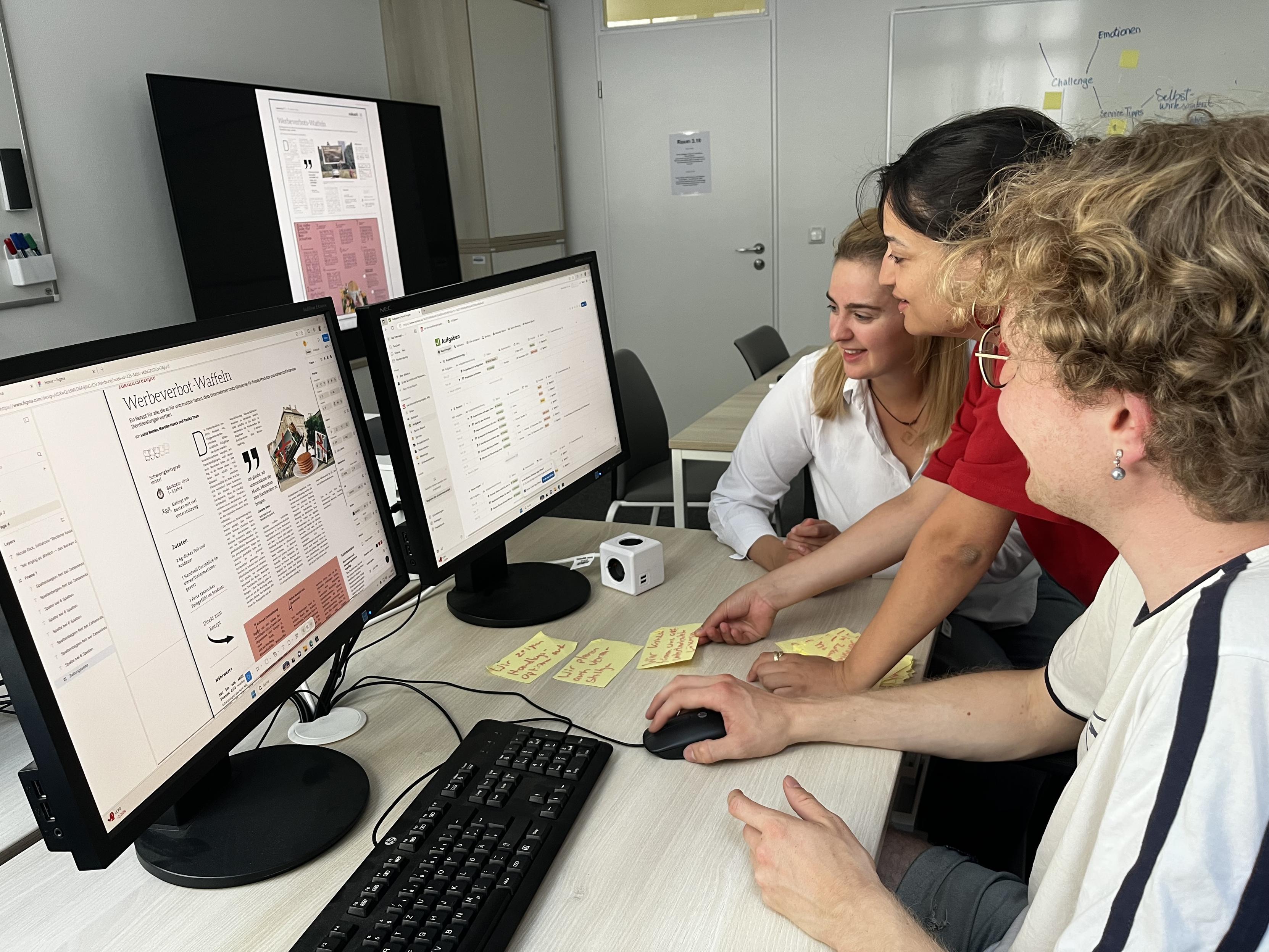 Person mit lockigem Haar arbeitet an einem Schreibtisch mit zwei Computermonitoren, auf denen Webseiteninhalte und Datenbankdetails angezeigt werden.