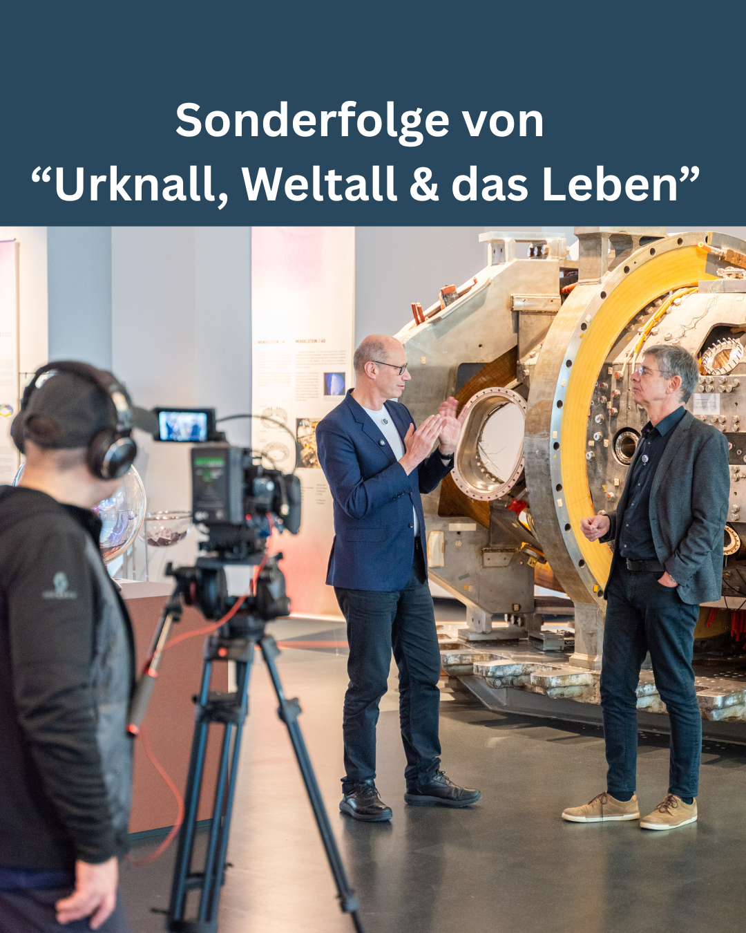 Kameramann filmt, wie Thomas Klinger und Hartmut Zohm sich stehend unterhalten. Im Hintergrund ein Segment des alten Stellarators Wendelstein 7-AS